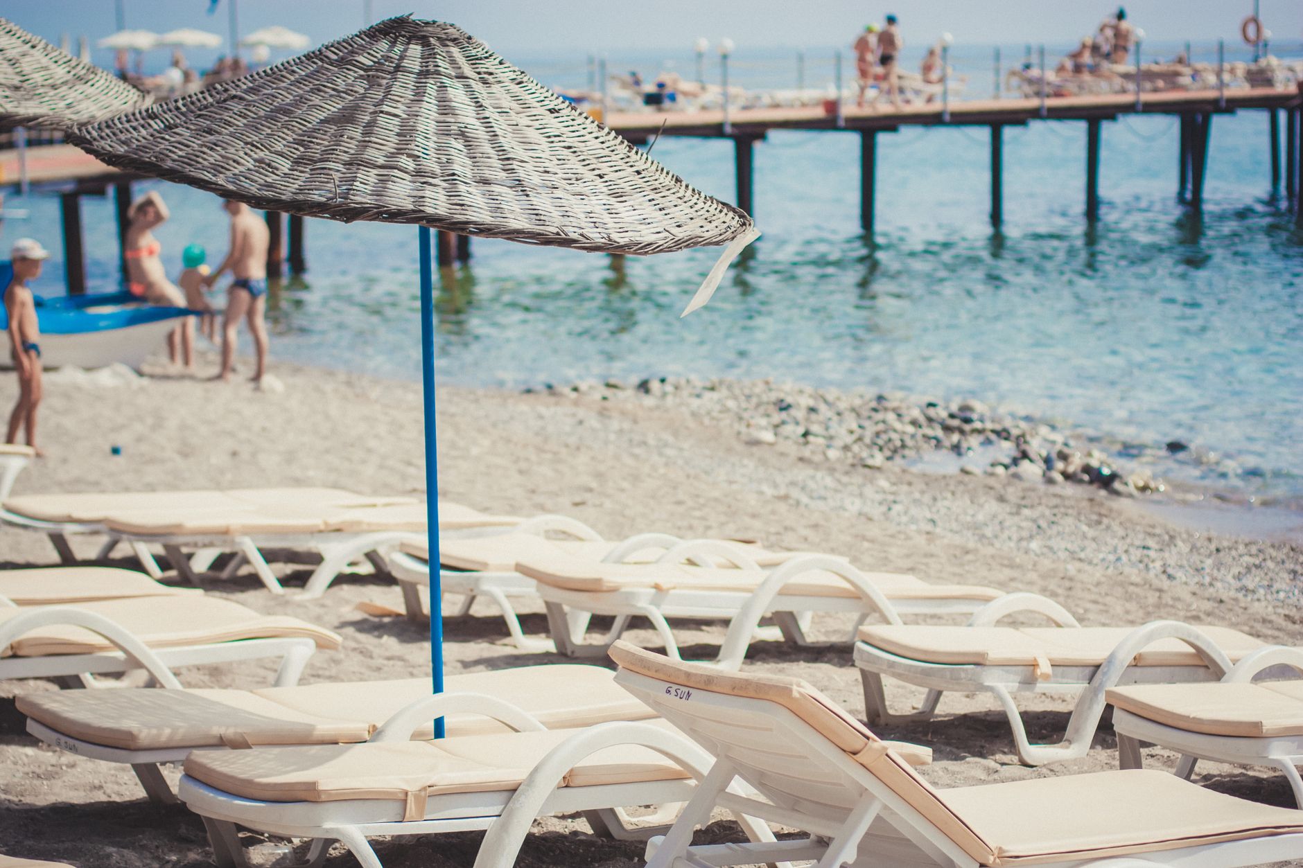 Relaxing beach scene with empty sun loungers and straw umbrellas by the sea.