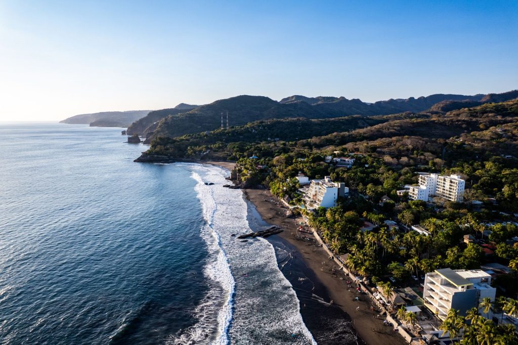 A stunning aerial view of El Zonte Beach, showcasing the coastline and surrounding hills in El Salvador.