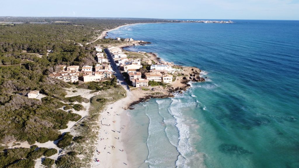 A stunning aerial view of Ses Covetes beach and coastline in Mallorca, showcasing serene turquoise waters and sandy shores.