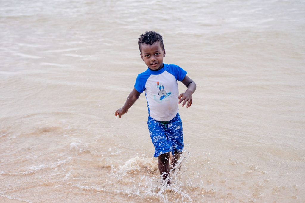 Young boy having fun in shallow ocean water during a sunny day.