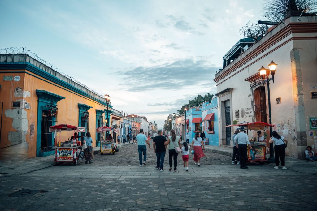 Evening street scene in Oaxaca City with people strolling and vibrant architecture.
