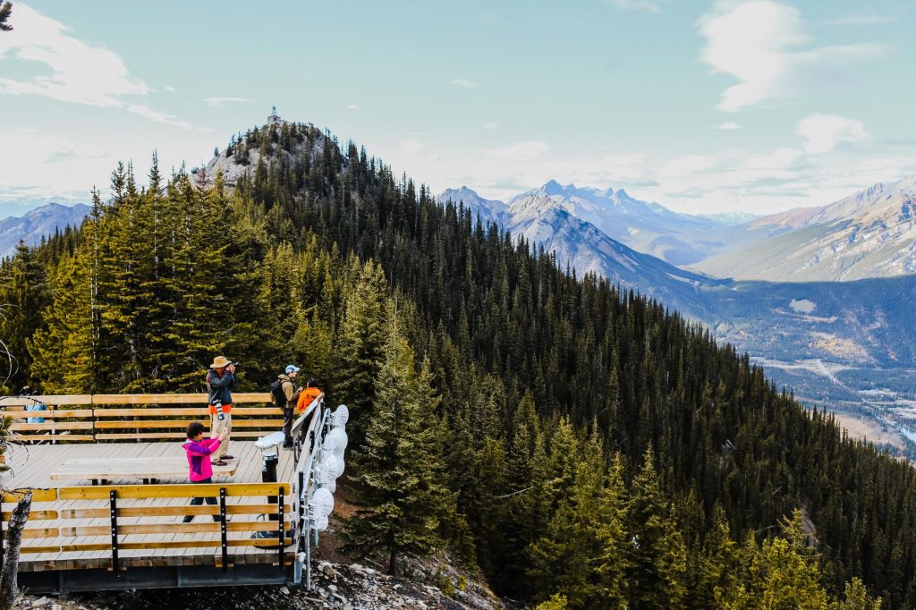 Tourists enjoying the stunning view from a mountain observation deck in Canada.