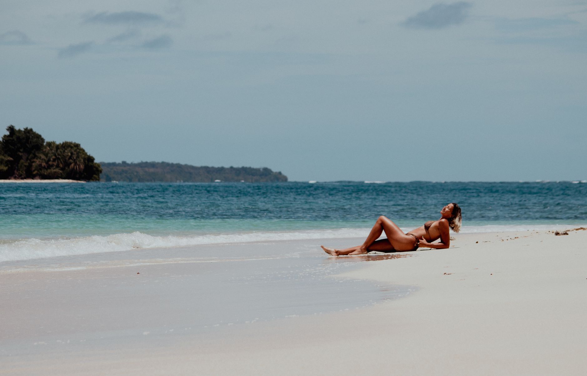 Woman sunbathing on a tranquil beach in Bocas del Toro, Panama, enjoying the serene coastline.