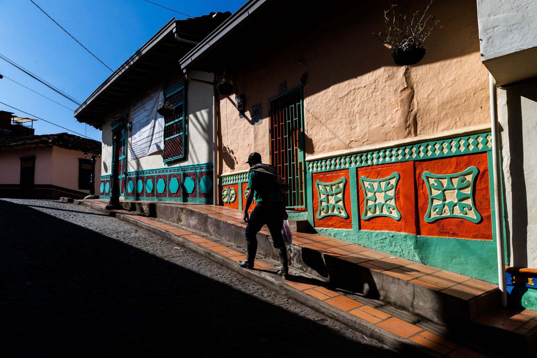 Man walking on colorful street in Guatapé, showcasing traditional Antioquian architecture.