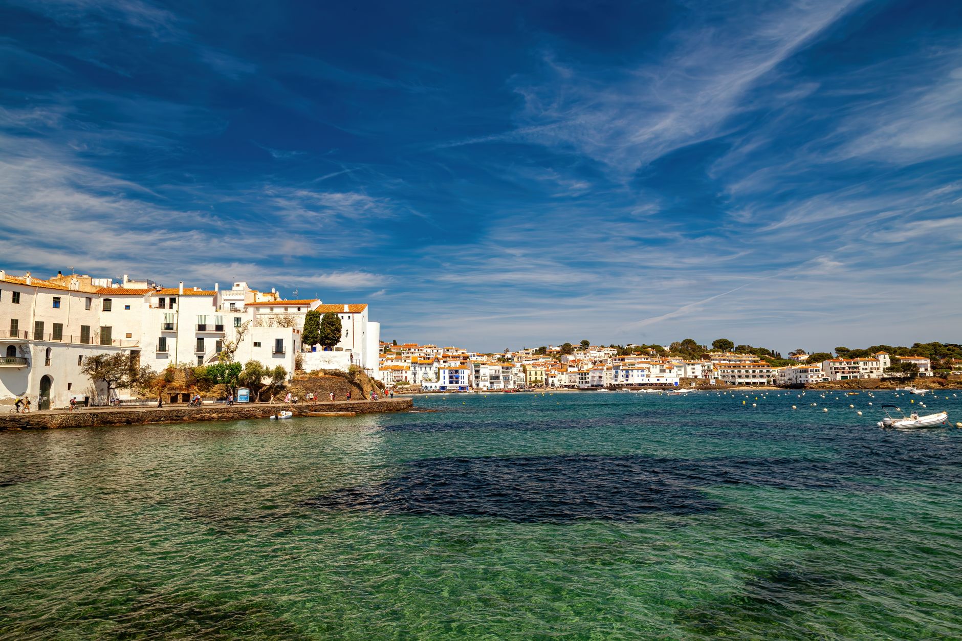 Picturesque coastal view of Cadaqués village in Cataluña with blue skies and shimmering waters.