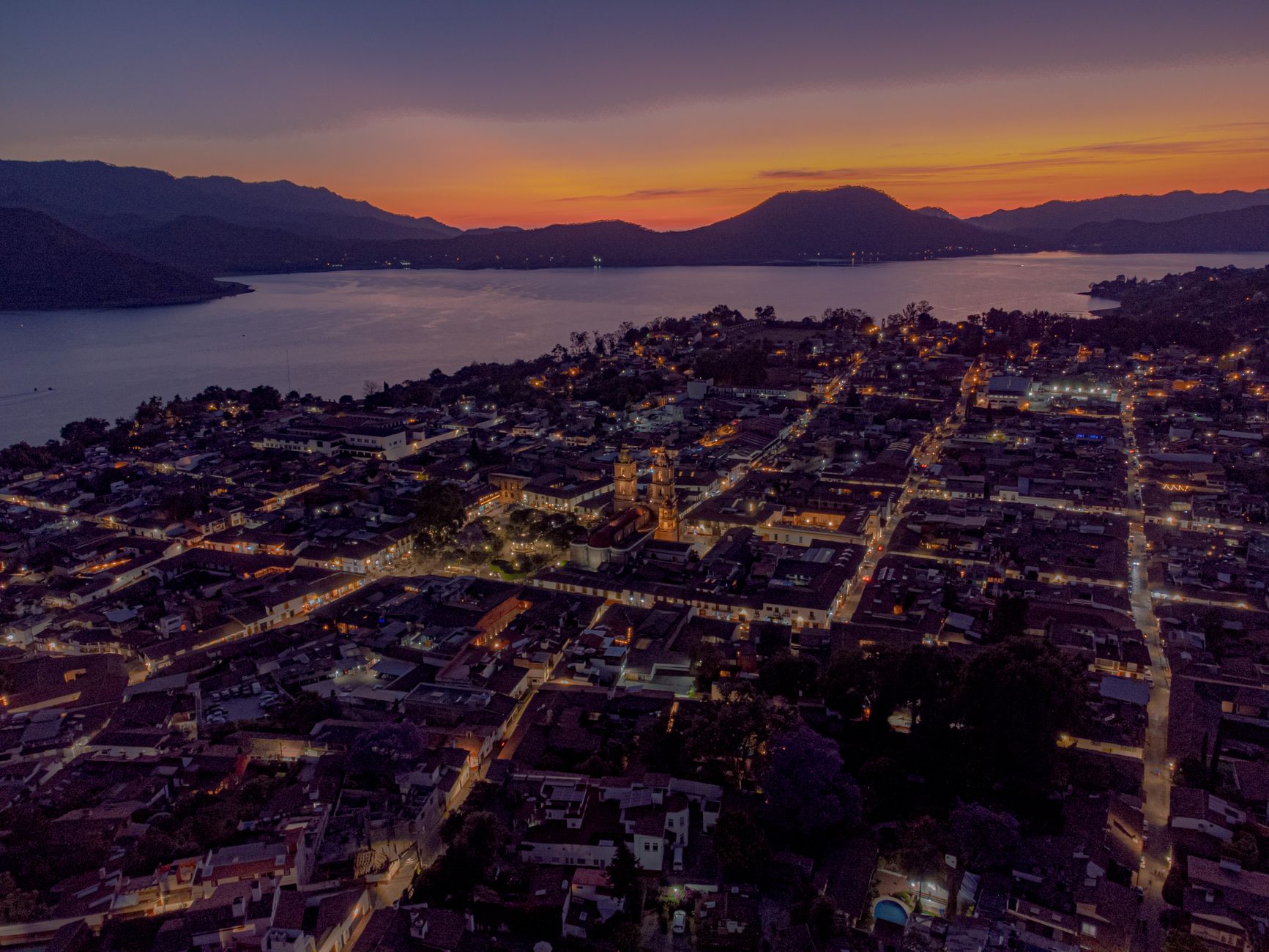 Stunning aerial shot of Valle de Bravo's cityscape at sunset with mountains and lake.