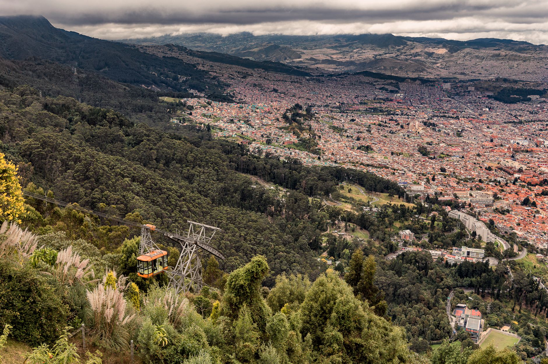 Explore Bogotá's vast cityscape and lush hills from a cable car in this stunning aerial view.