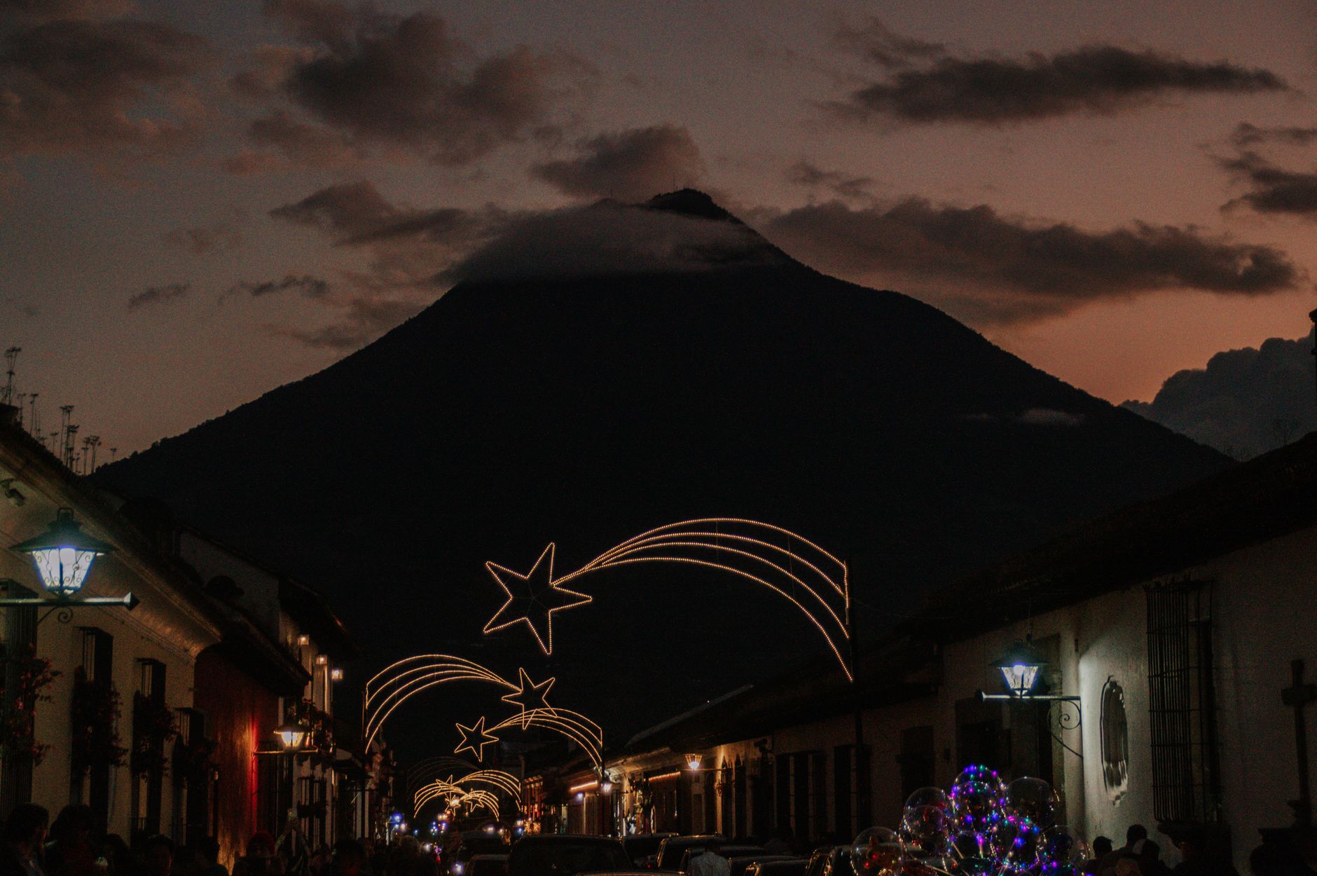 Beautiful Christmas decorations light up streets of Antigua Guatemala with the Agua Volcano in the background.