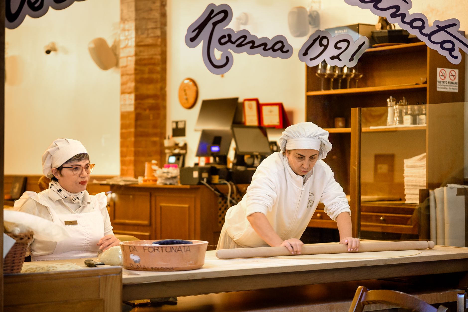 Two chefs skillfully prepare fresh pasta in a traditional Bologna restaurant kitchen, capturing Italian culinary art.