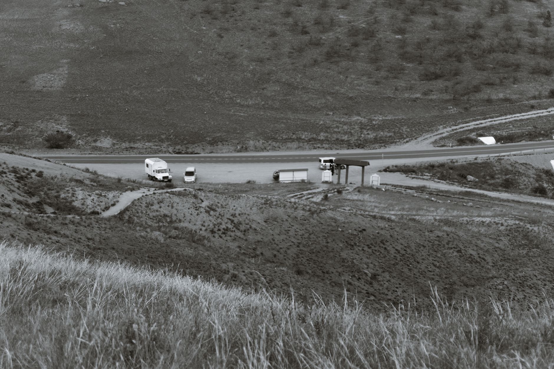 Black and white of transport parked on roadway between high dry mounts in daytime