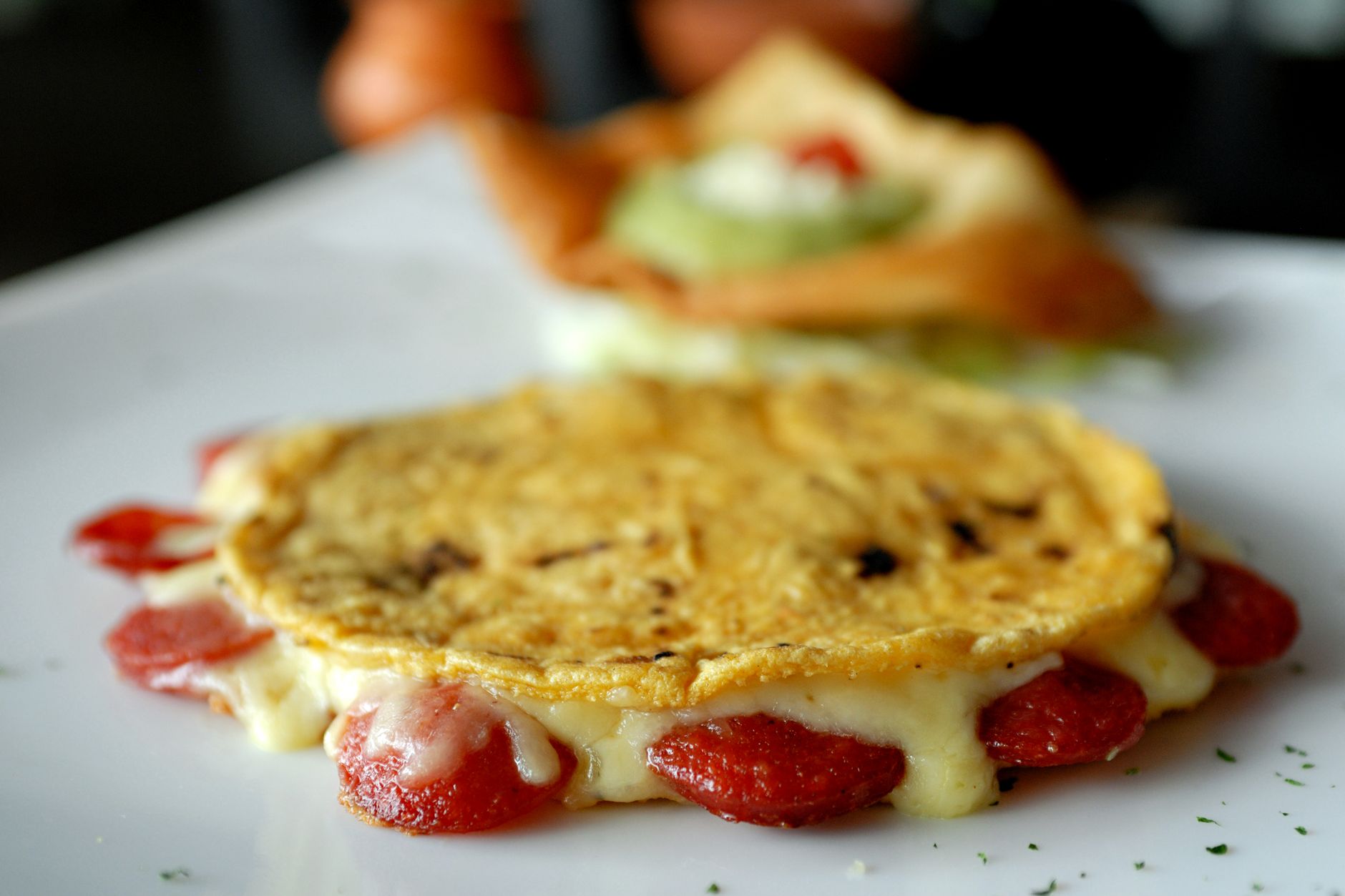 Mouthwatering close-up of a melted cheese and sausage quesadilla, perfect for a savory meal.