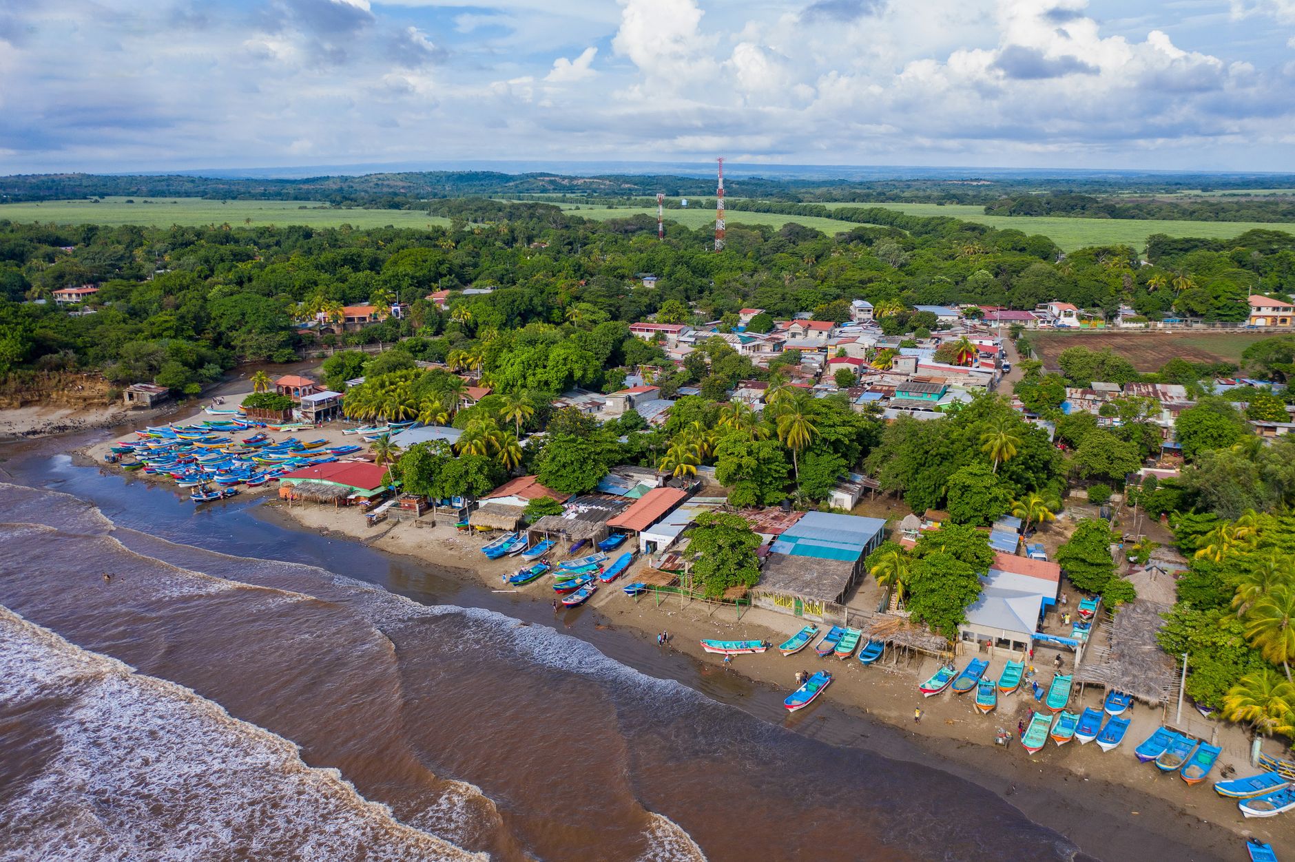 Scenic aerial view of a vibrant coastal town in Nicaragua with colorful boats and lush greenery.