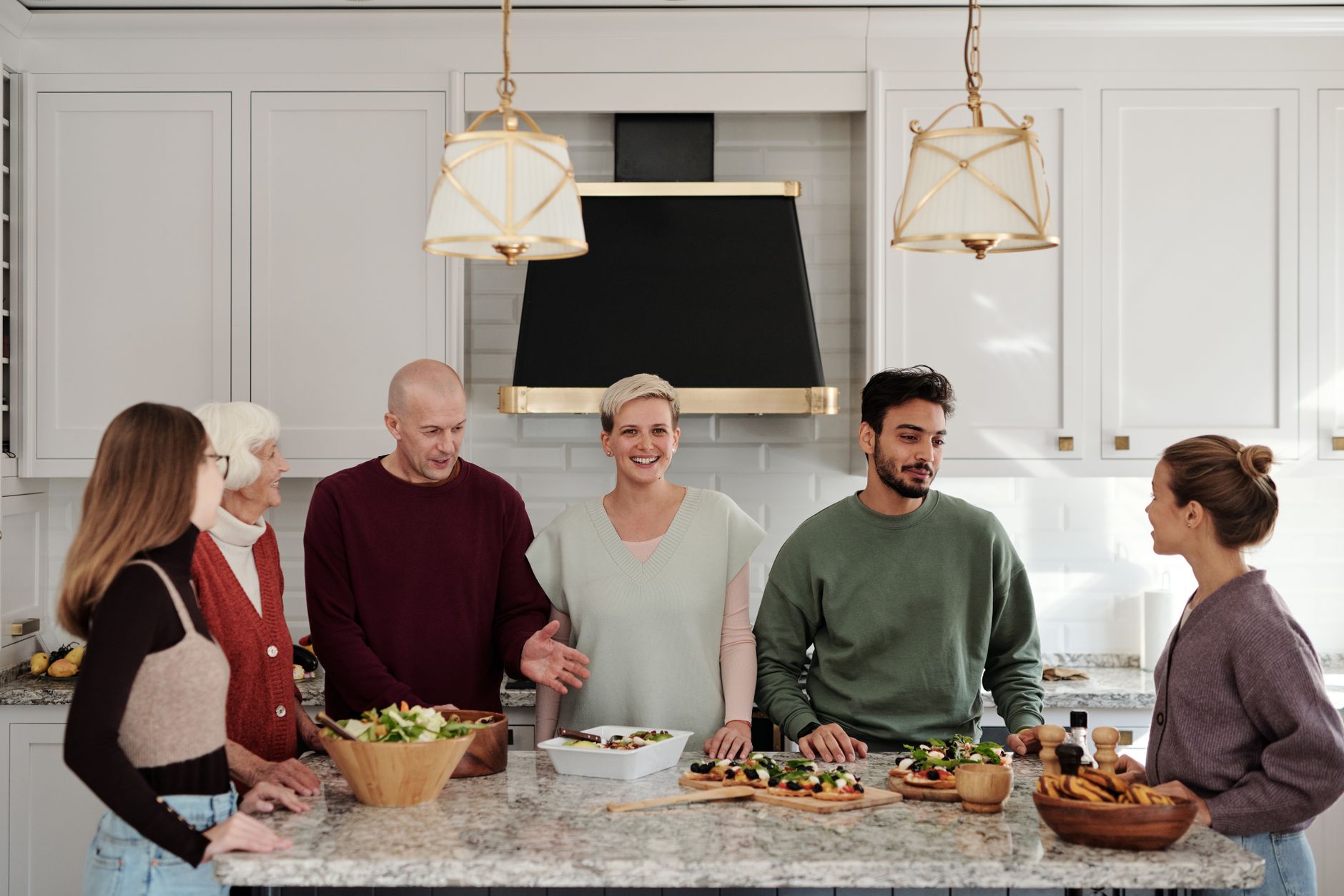 A multi-generational family enjoying a meal preparation together in a bright kitchen.