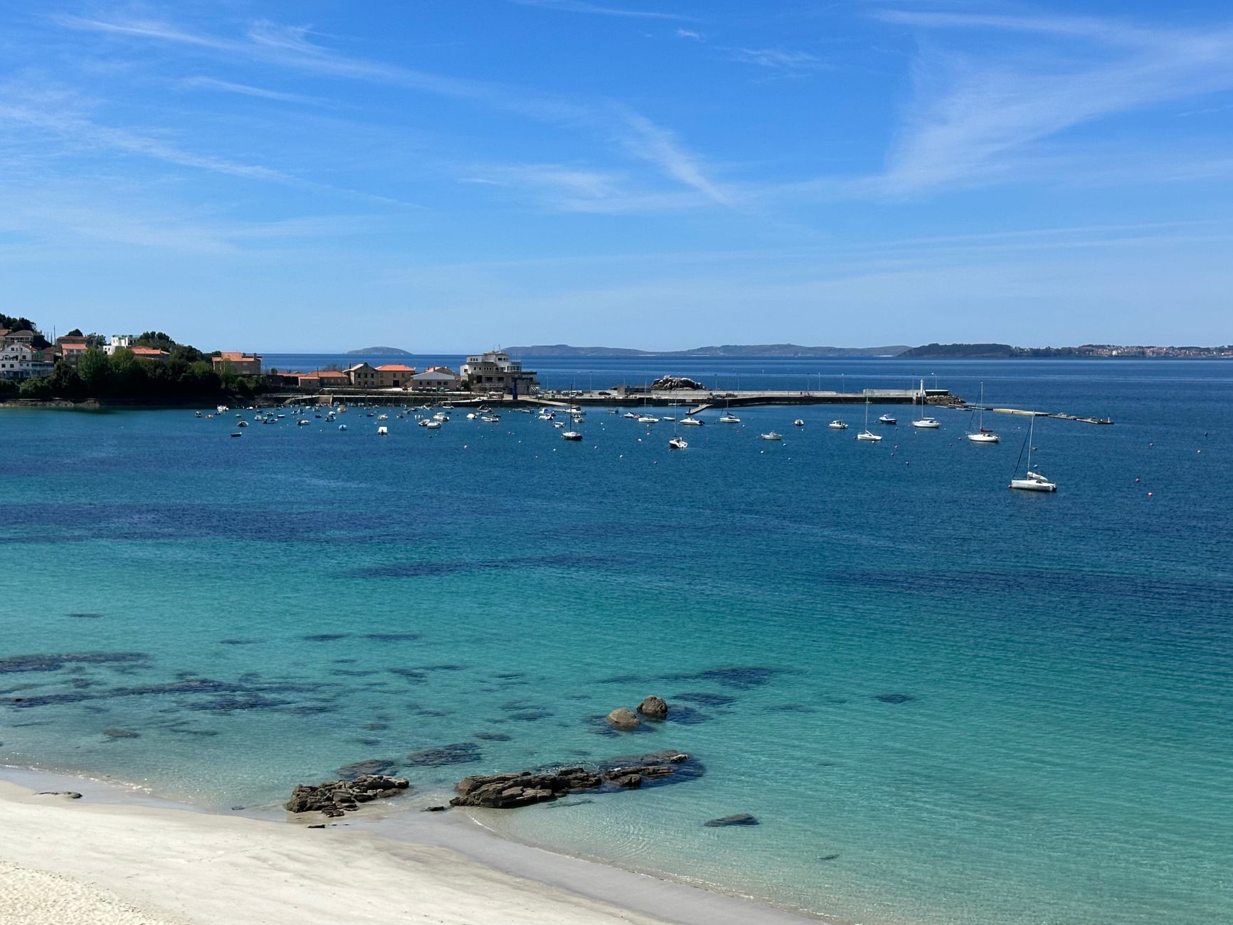 Discover the serene beauty of Ría de Vigo from a tranquil beach with clear waters and vibrant scenery.