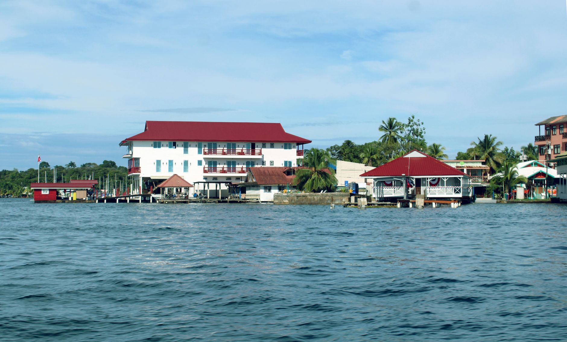 Charming waterfront scene of Bocas del Toro buildings with red roofs and palm trees.
