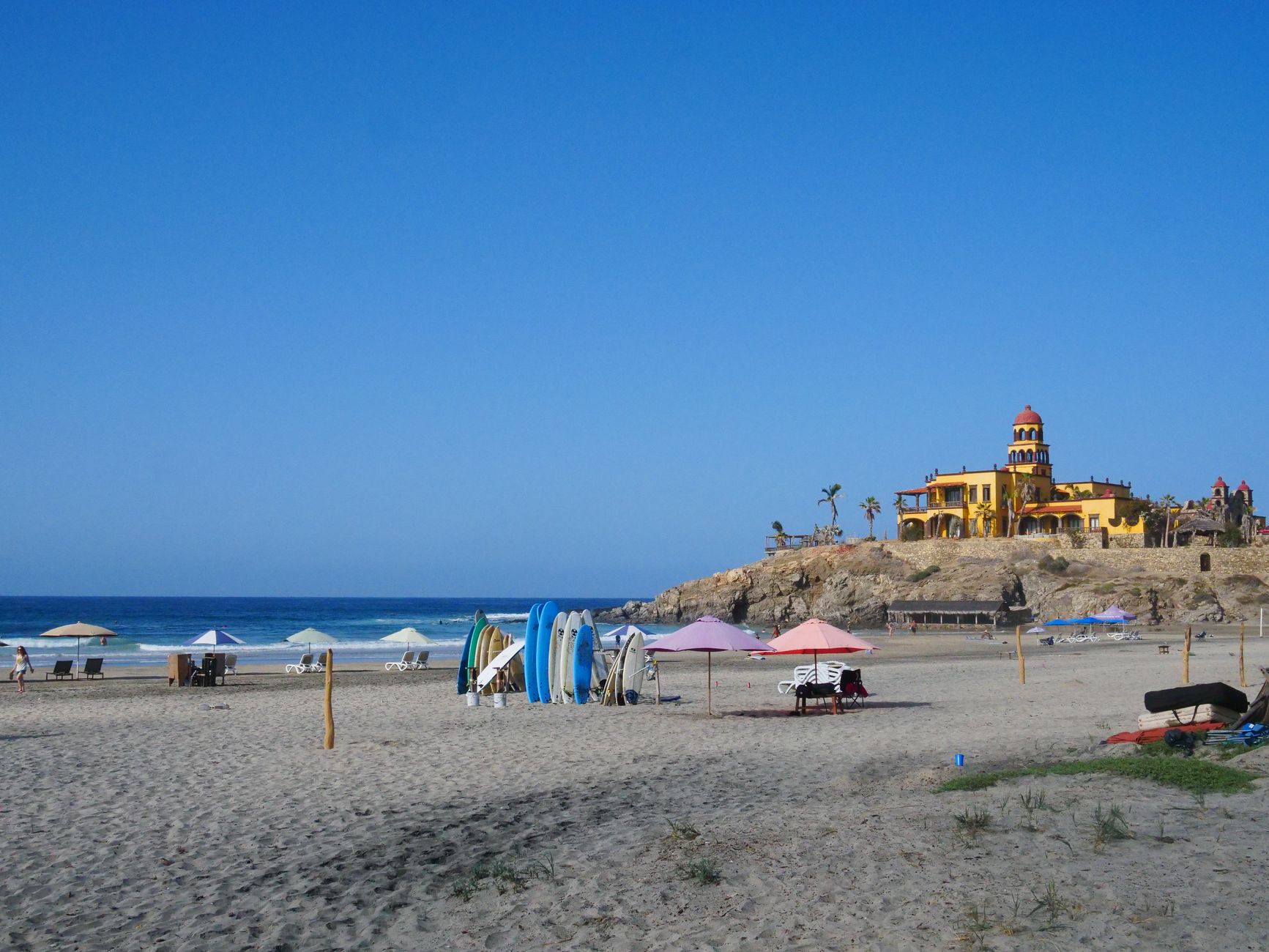 Cerritos Beach in Mexico with colorful umbrellas and a vibrant building by the ocean.