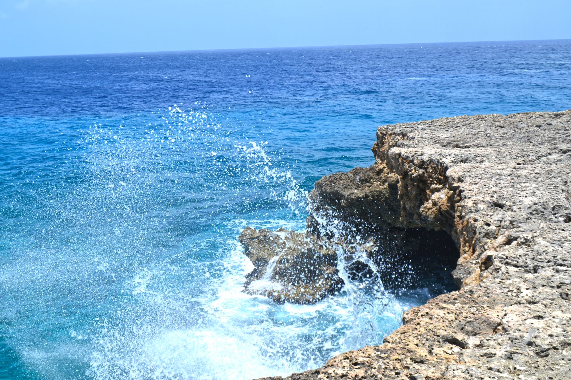 Vibrant ocean waves splashing against the rocky shoreline of Curaçao. A perfect tropical seascape for travel inspiration.
