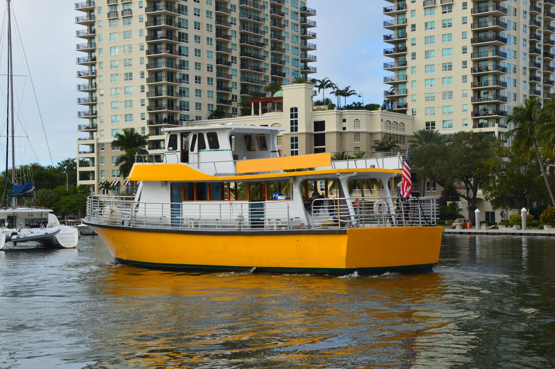 Yellow tour boat cruising Fort Lauderdale canal with high-rise buildings in view.