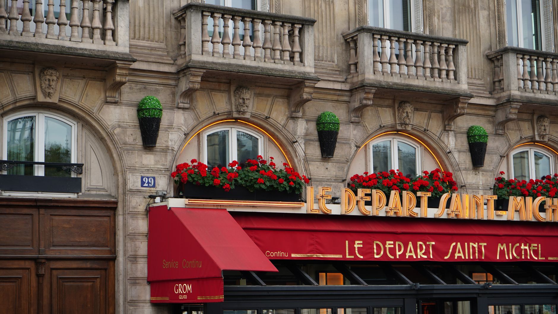 Elegant Parisian café with red awning and floral decor on a sunny day.