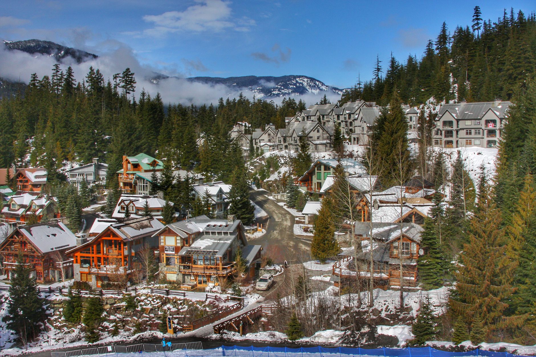 Charming snowy village with coniferous trees in Whistler, BC, under blue skies.
