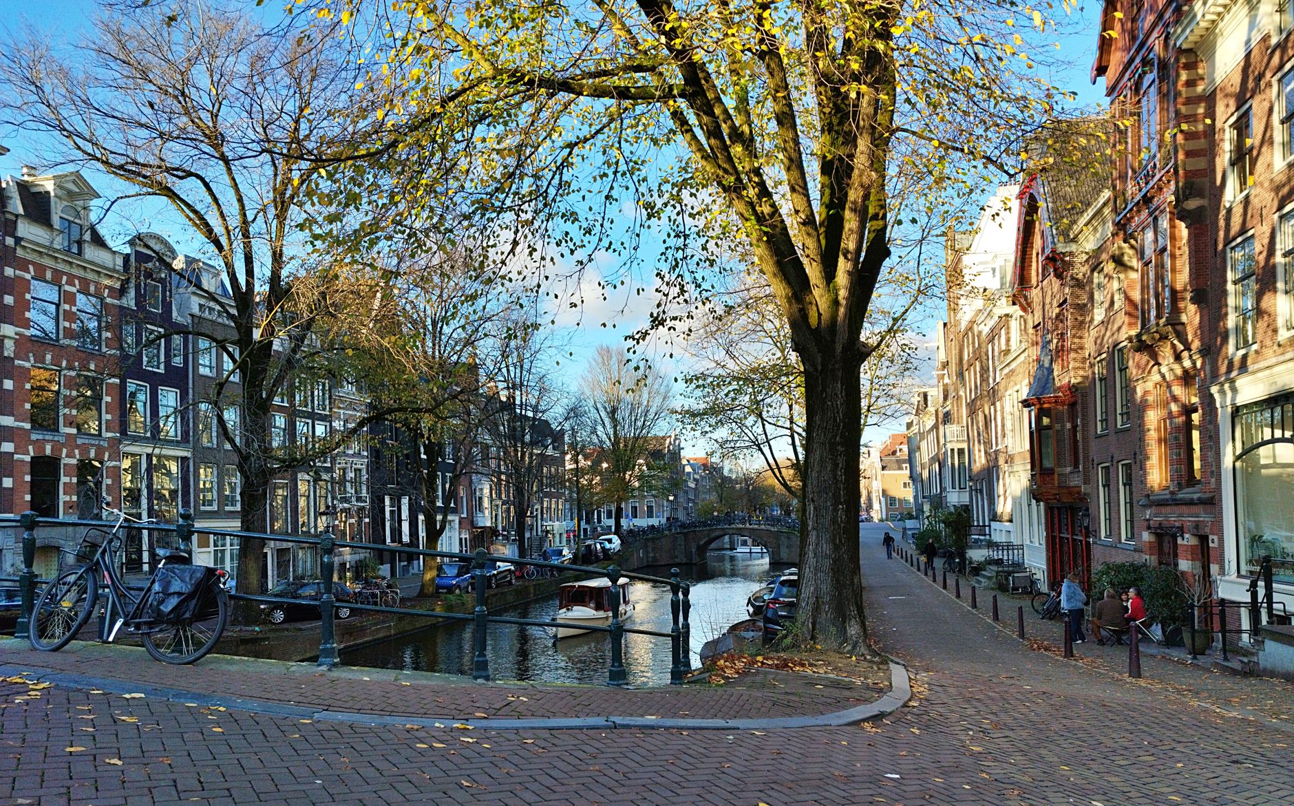 Picturesque autumn view of Amsterdam canal with bicycles, trees, and historic architecture.