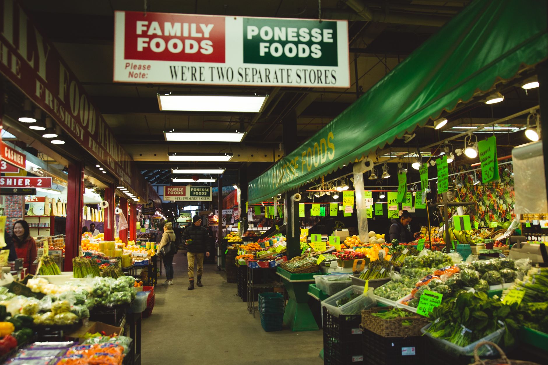 Anonymous people near counters with assorted fresh appetizing fruits and vegetables in local grocery market