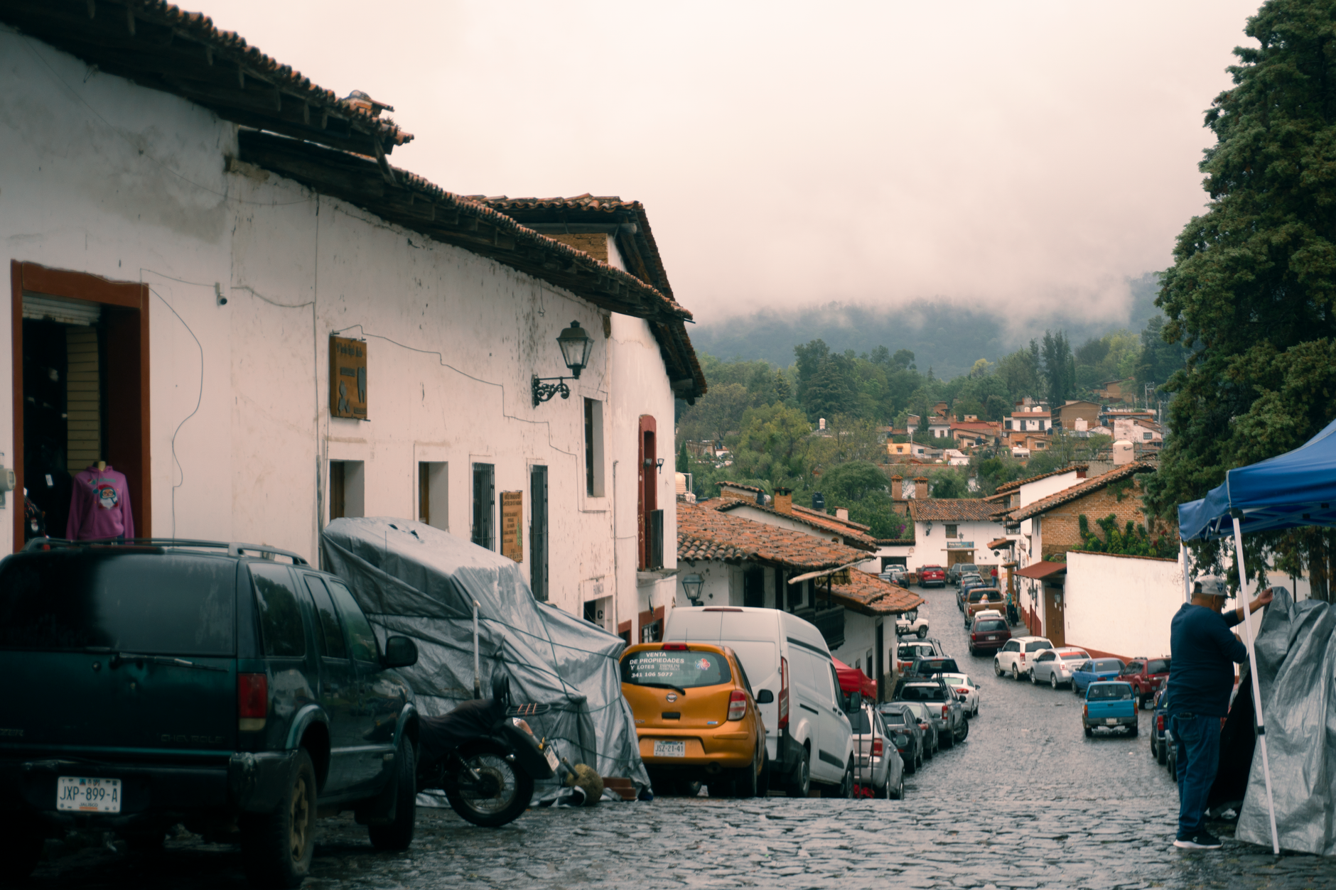 Cobblestone street in Tapalpa, Mexico with traditional architecture and misty hills.