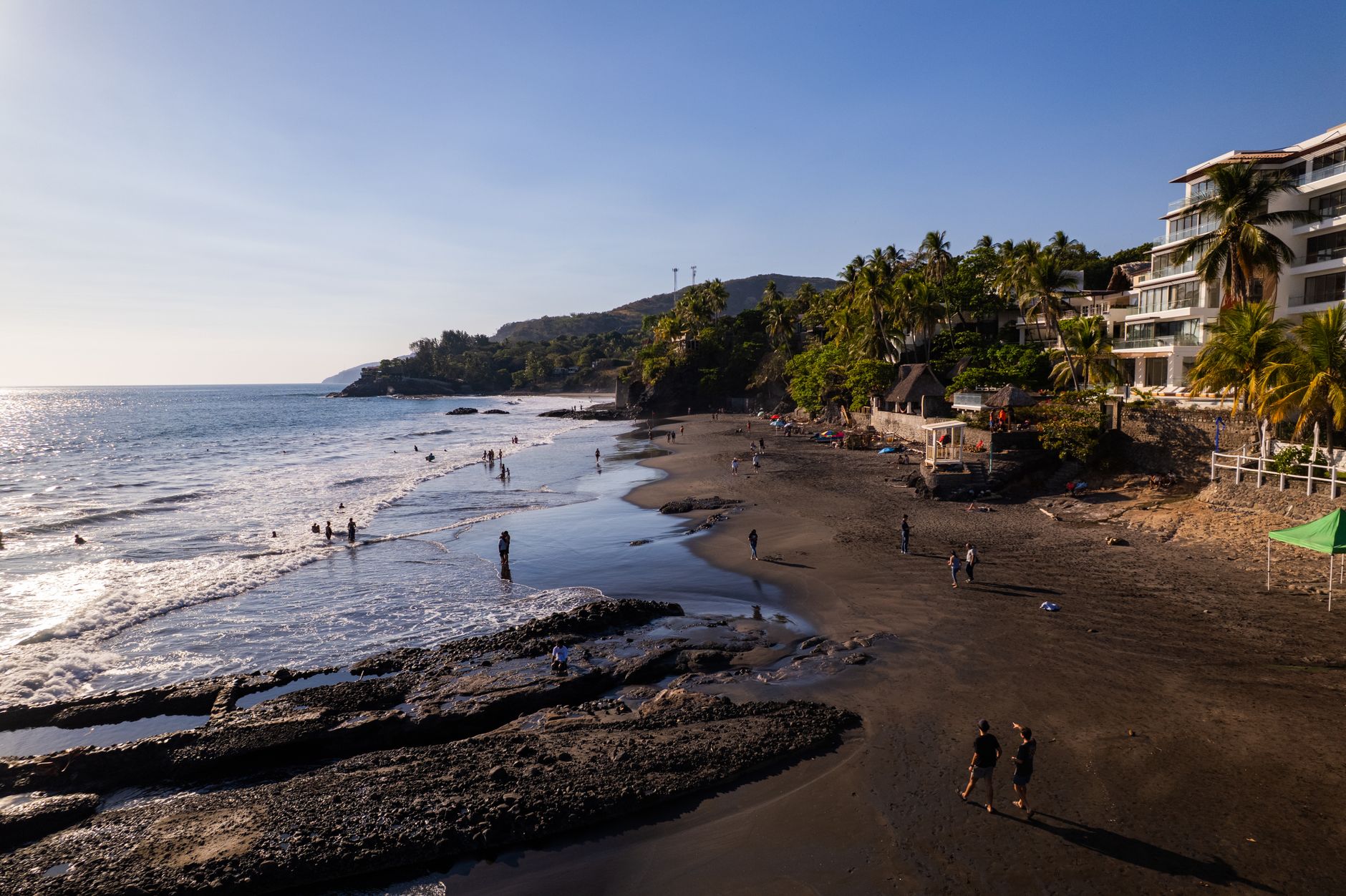 A beautiful sunny beach scene in El Zonte, El Salvador with people enjoying the shoreline.