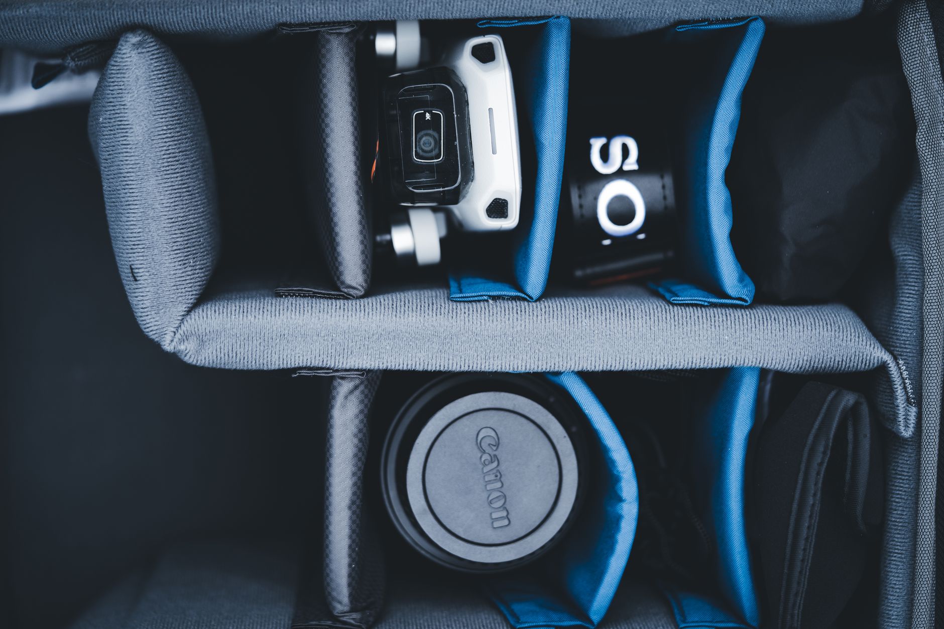 Flat lay of a camera backpack with organized gear, compartments, and gadgets for travel.