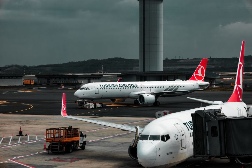 Turkish Airlines planes parked at an airport with a control tower in the background.
