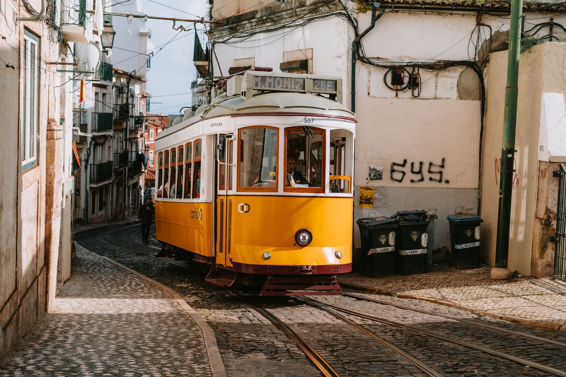 Historic yellow tram on Lisbon's cobblestone street, capturing a classic European scene.