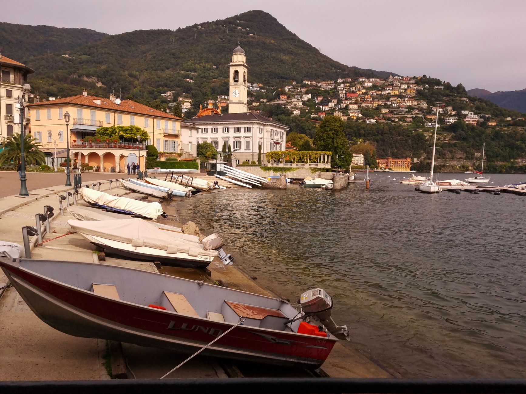 Peaceful harbor scene at Lake Como with boats and scenic hillsides.