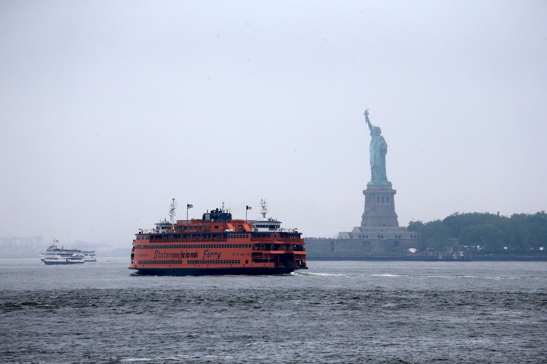 Staten Island Ferry traverses misty waters near the iconic Statue of Liberty in New York Harbor.