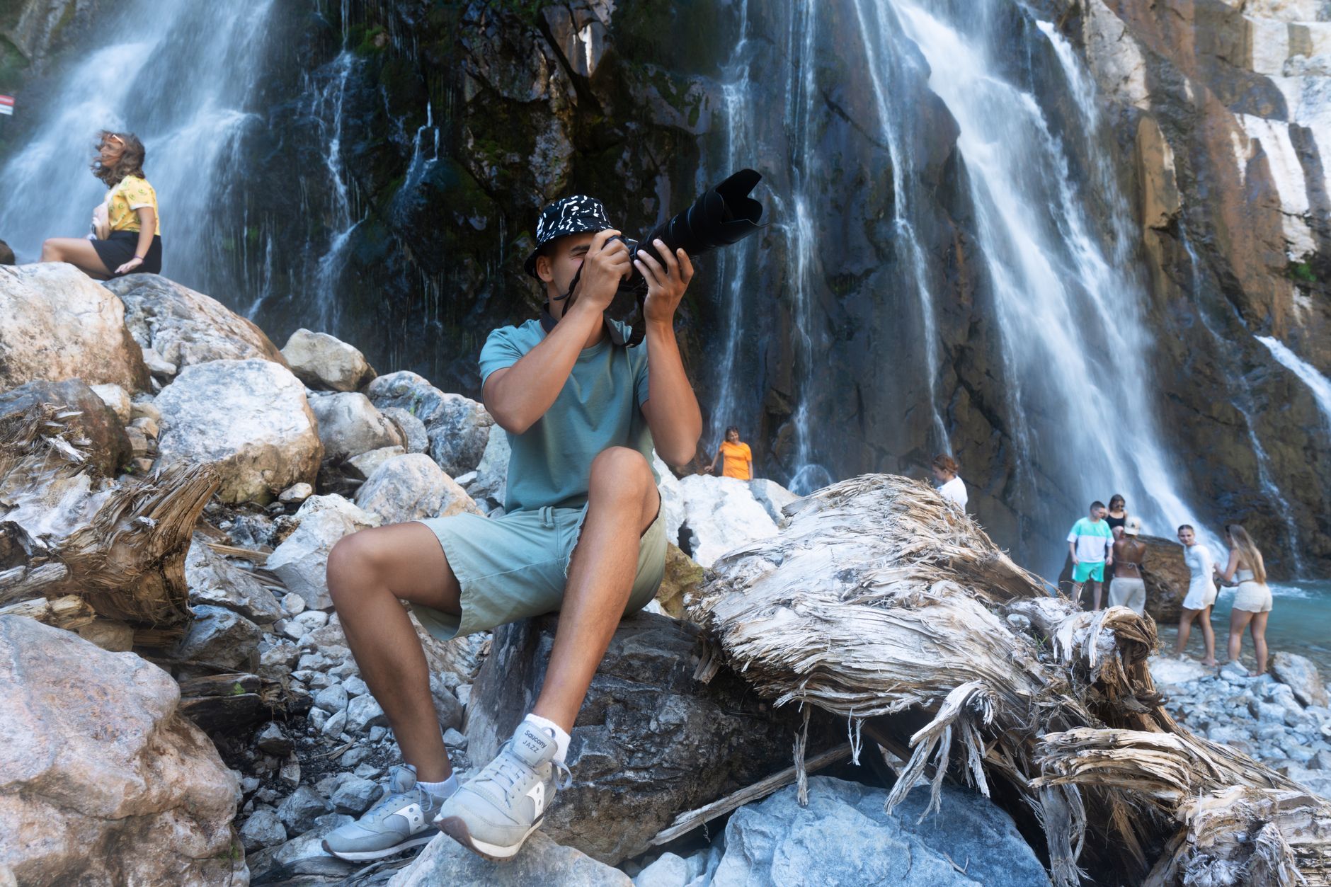A photographer captures a waterfall scene in Гагра with tourists enjoying the view.