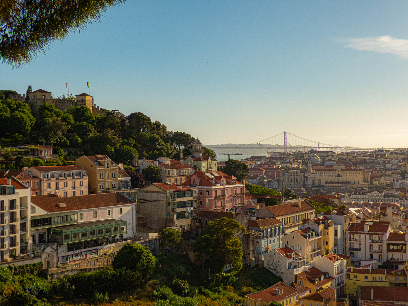 Explore Lisbon's colorful architecture with a view of the iconic 25 de Abril Bridge.