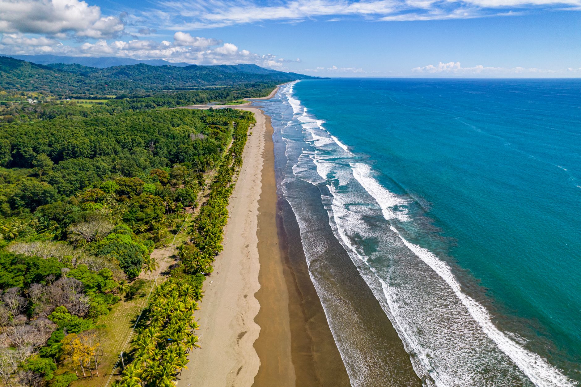 A breathtaking aerial view of the coastline at Puntarenas, Costa Rica, showcasing pristine beaches and lush greenery.