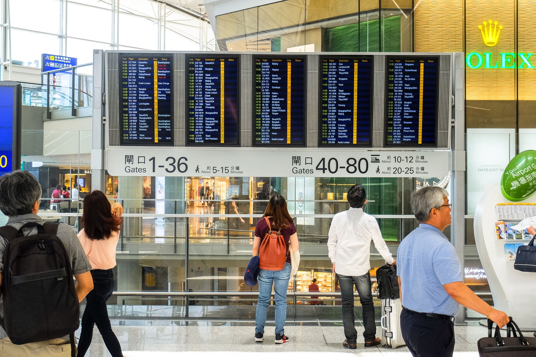 Passengers checking the departure board at Hong Kong International Airport terminal.