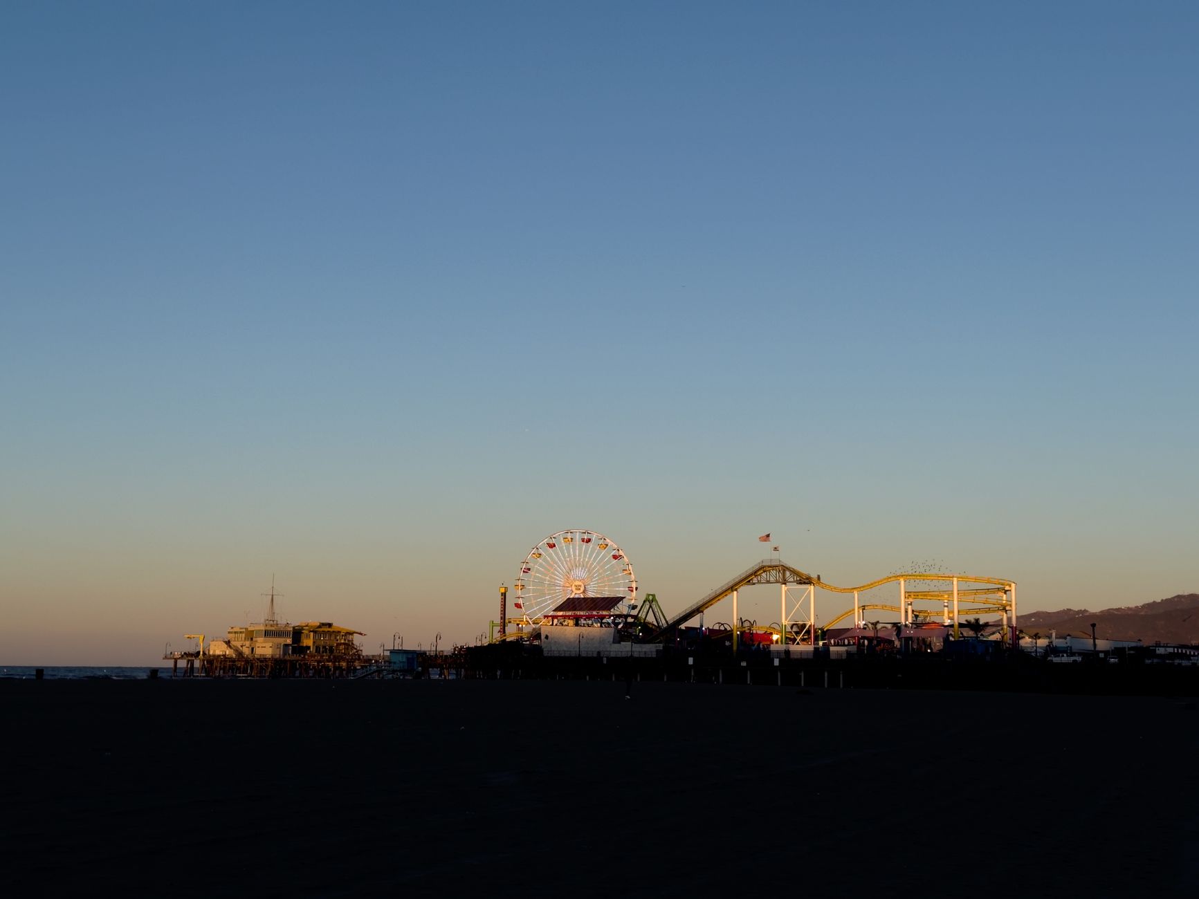 Silhouette of Santa Monica Pier featuring a Ferris wheel during a serene sunset in California.
