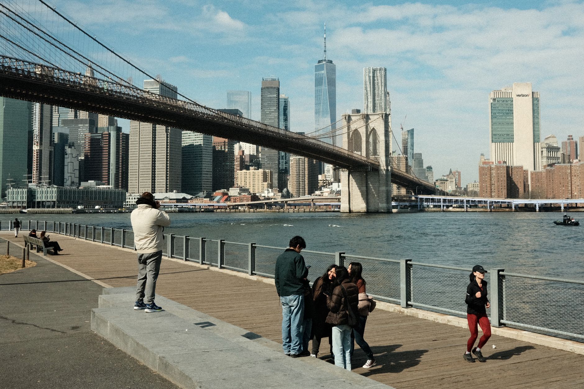Scenic view of Brooklyn Bridge and New York City skyline with people on promenade.