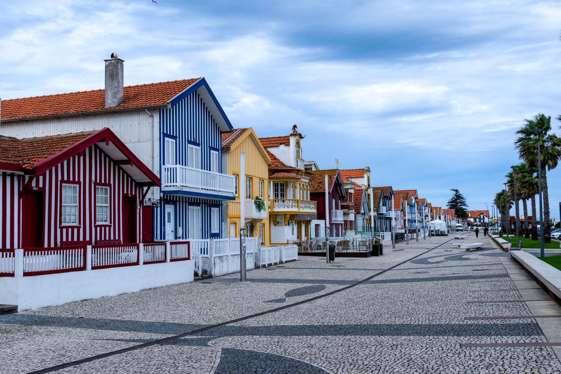 Vibrant striped cottages lining a coastal promenade in Costa Nova, Portugal.