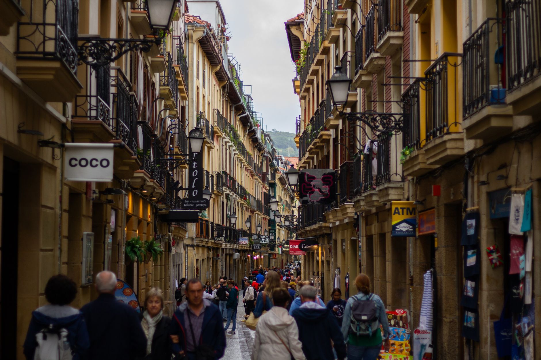 Crowded pedestrian street in San Sebastián's old town, vibrant day scene.