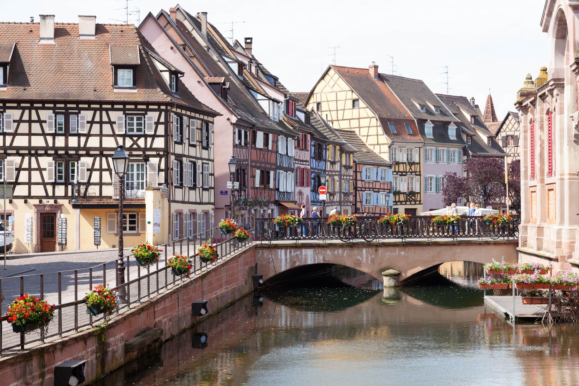Scenic view of Colmar's half-timbered houses and picturesque bridge over a peaceful canal.