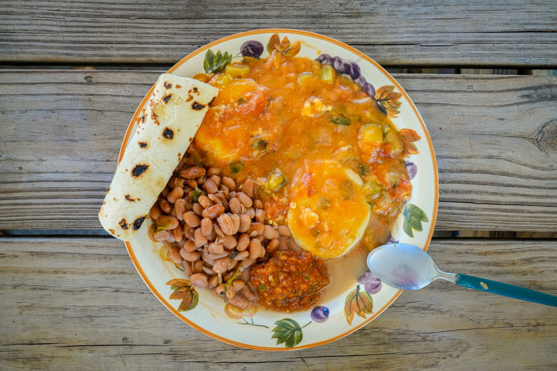 Delicious traditional Tex-Mex breakfast featuring eggs, beans, salsa, and tortilla on a rustic wooden table.