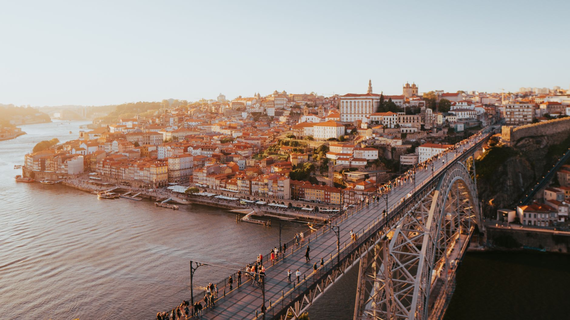 A stunning aerial view of Porto's historic cityscape and Dom Luís I Bridge over the Douro River at sunset.