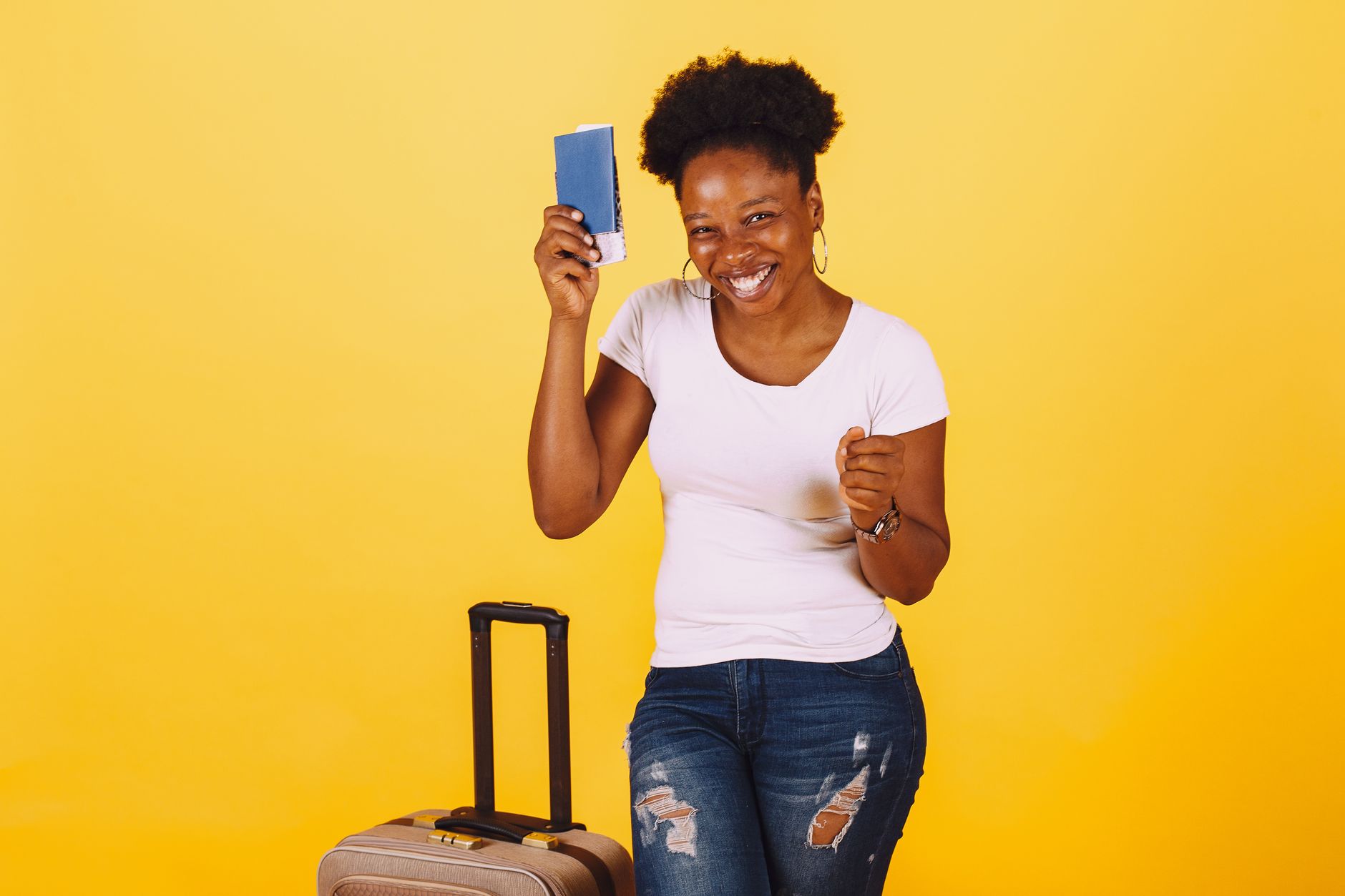 Joyful woman holding passport and luggage, ready for a trip. Bright, cheerful yellow background.