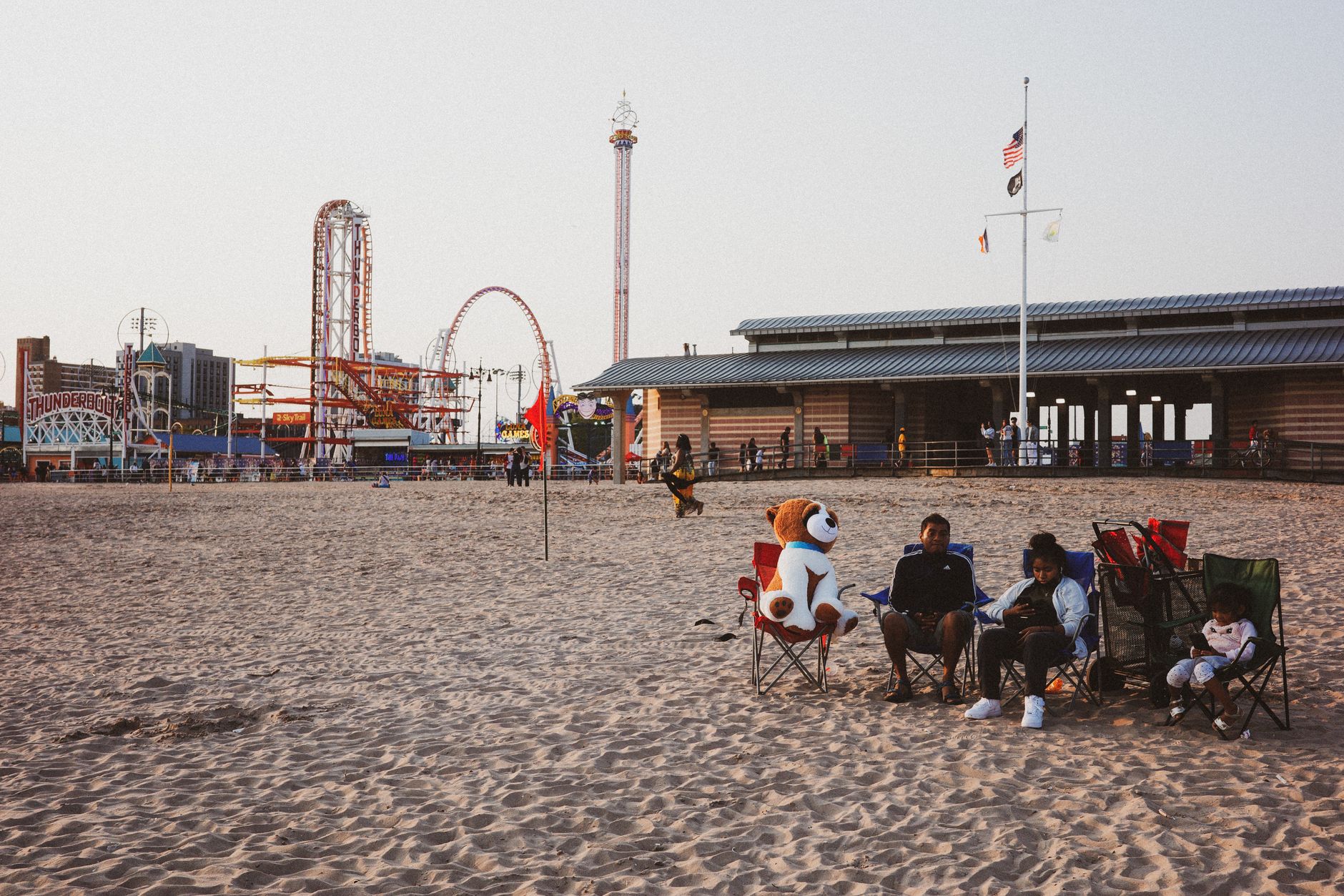 A family enjoys a day of leisure at the iconic Coney Island beach with an amusement park backdrop.