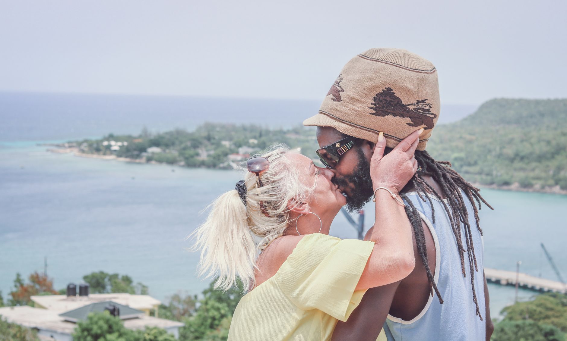 A multiracial couple shares a romantic kiss overlooking the ocean in Jamaica.