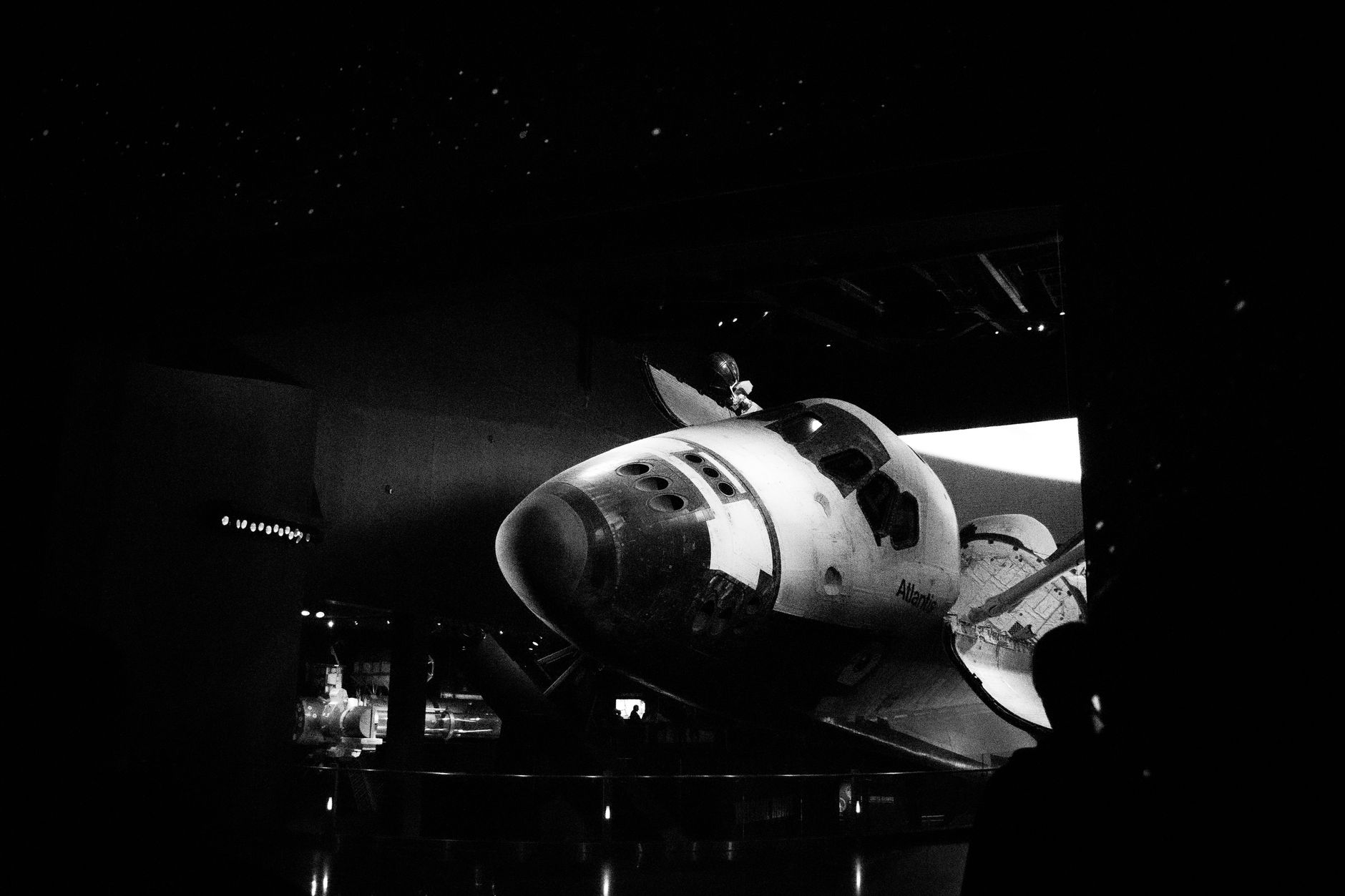 Dramatic black and white image of a space shuttle exhibit in a museum.