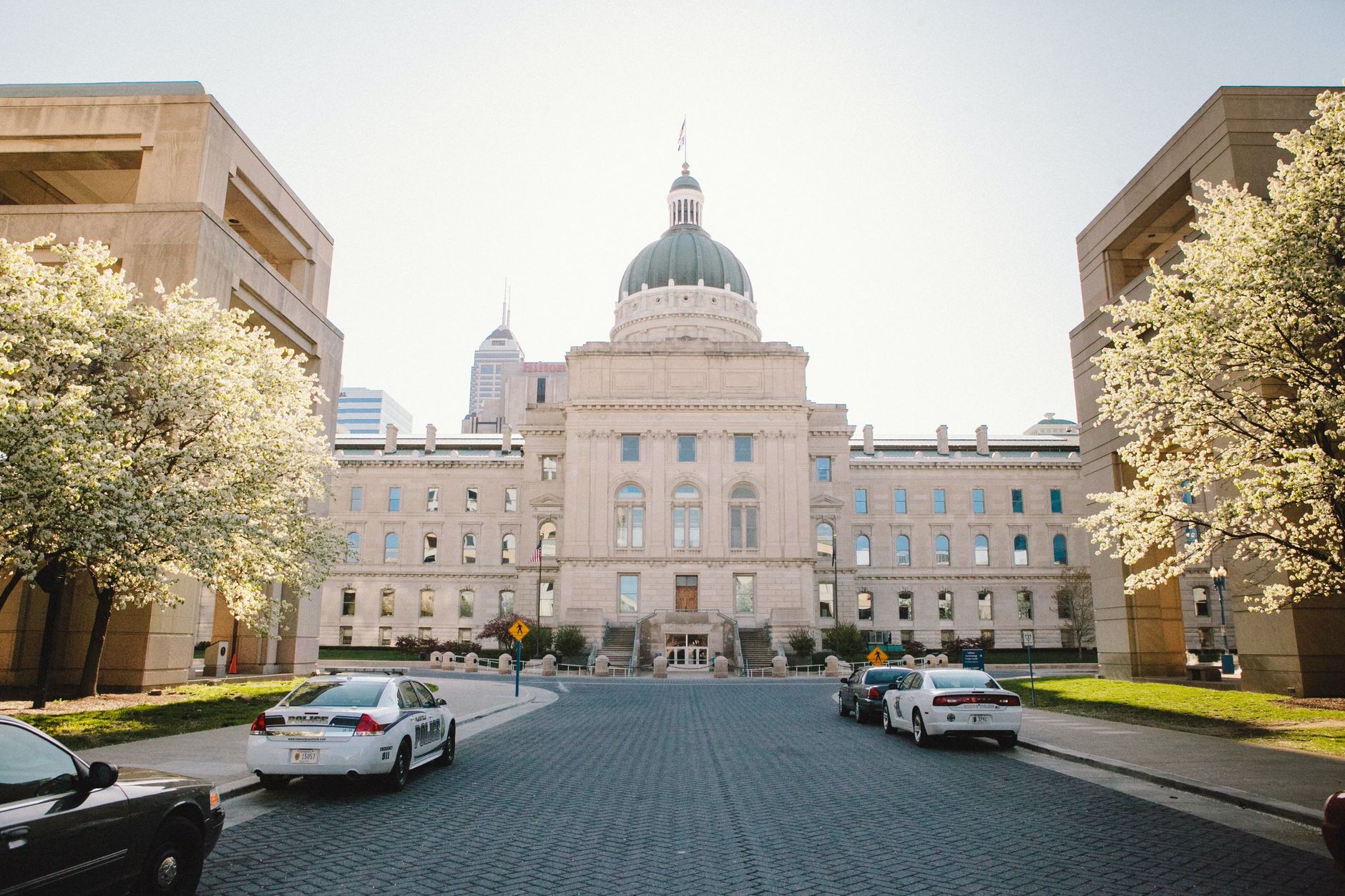 Historic Indiana State Capitol Building in Indianapolis during springtime with blooming trees.