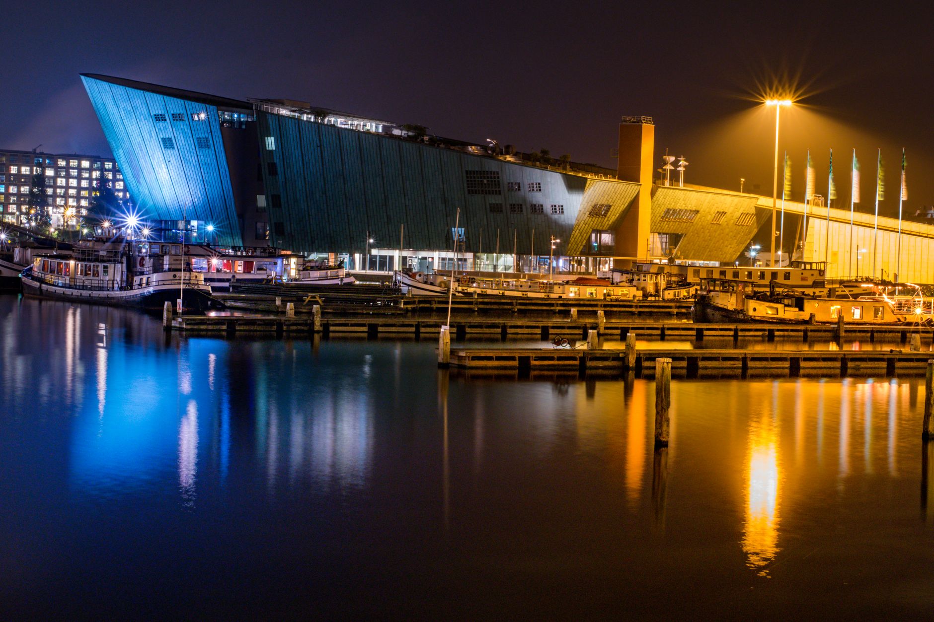 Night view of NEMO Science Museum and harbor reflections in Amsterdam.